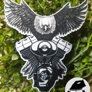 Peut inclure: Patch thermocollant représentant un aigle noir et blanc aux ailes déployées, perché sur un moteur de moto détaillé. Le patch est doté d'un dos thermocollant et porte l'inscription "IRON-ON".
