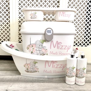 May include: A white baby bath set with a cartoon elephant on a swing and pink roses. The set includes a baby bathtub, storage containers, and two lotion dispensers. The name "Mizzy Marie Roberts" is written in pink script on the items.