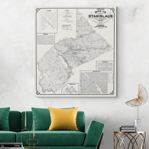 May include: A framed vintage map of Stanislaus County, California, from 1906. The black and white map includes detailed city and town layouts, with insets for Ceres, Newman, Turlock, Oakdale, and Modesto. The map is displayed on a white wall.