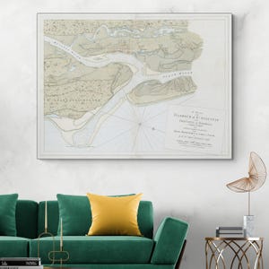 Puede incluir: Un mapa vintage enmarcado titulado "A Plan of the Harbour of St. Augustin, Province of Georgia". El mapa presenta ilustraciones detalladas de la costa, los ríos y las áreas circundantes, con un enfoque en el puerto. El mapa está en un marco blanco.