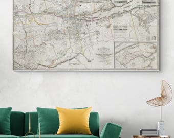 May include: A framed antique map with detailed cartography, featuring a network of lines and geographical features. The map is predominantly in grayscale with subtle color accents. It hangs above a green sofa with a yellow pillow.