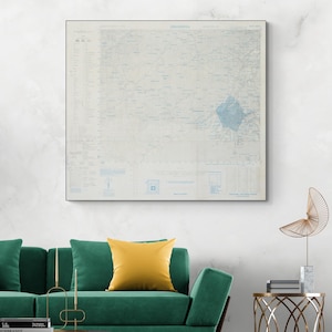 Puede incluir: Impresión enmarcada de un mapa en tonos azul claro y blanco, con información geográfica detallada. La impresión, etiquetada como "IRIB INDIA", cuelga sobre un sofá verde con un cojín amarillo. Un elemento decorativo.