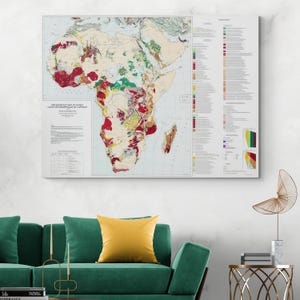 May include: A large canvas print of a metamorphic map of Africa, featuring a detailed geological illustration with various colors. The map is displayed above a green sofa with a yellow pillow and a gold side table.