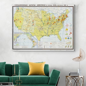 Puede incluir: Un mapa vintage enmarcado de los Estados Unidos, con texto en ruso, cuelga de una pared sobre un sofá verde con un cojín amarillo. El mapa presenta ilustraciones y marcas detalladas, con una combinación de colores amarillo y marrón.