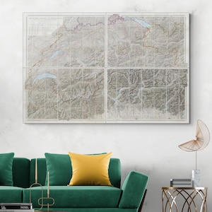 Pode incluir: Uma obra de arte de parede de quatro painéis com um mapa vintage da Suíça. O mapa, em tons de cinza, bege e castanho, mostra linhas topográficas detalhadas e texto. A obra de arte está acima de um sofá verde com uma almofada amarela.