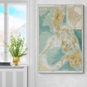 Può includere: Mappa vintage delle Filippine, con dettagliata topografia in tonalità marroni e beige su sfondo azzurro e verde chiaro. Il testo giapponese è visibile in alto e in basso, il tutto incorniciato.