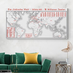 May include: A framed world map with text in German, "Die Jüdische Welt - Anfang 1926 - 18 Millionen Seelen" in red. The map shows continents and countries in gray, with red dots and text indicating locations. The map is displayed above a green sofa.