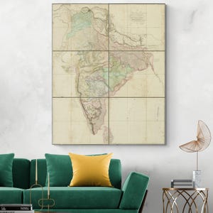 May include: A large framed map of India, split into six panels. The map shows detailed geographical information with colours like green, pink, and blue, set against a beige backdrop. The map is displayed above a green sofa with a yellow cushion.