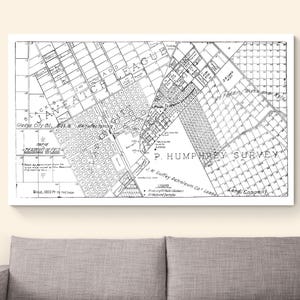 May include: Black and white vintage map print, framed in white. The map features detailed street layouts, labeled areas, and the text "P. Humphrey Survey." The map is displayed above a gray sofa.