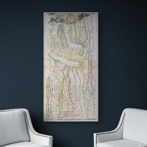 K&ouml;nnte beinhalten: Eine gerahmte Vintage-Karte mit detailliertem, farbenfrohem Design h&auml;ngt an einer dunkelblauen Wand. Die Karte weist eine Vielzahl von Farben auf, darunter Gr&uuml;n, Gelb und Rosa. Zwei wei&szlig;e Sessel sind darunter positioniert.