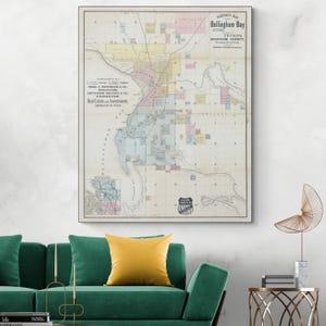 Könnte beinhalten: Eine gerahmte Vintage-Karte von Bellingham Bay, die die Stadt und ihre Umgebung zeigt. Die Karte verwendet verschiedene Farben, um Bereiche zu unterscheiden, mit Text, der Ortsnamen und geografische Merkmale angibt. Die Karte ist an einer Wand ausgestellt.