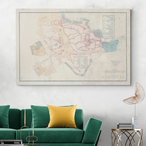 Può includere: Una stampa di mappa vintage incorniciata, con una rappresentazione cartografica dettagliata con linee rosse e blu e testo. La mappa è esposta sopra un divano verde con un cuscino giallo e un accento decorativo dorato.