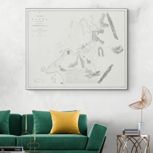 Könnte beinhalten: Ein gerahmter Vintage-Kartendruck mit einer detaillierten Graustufen-Illustration. Die Karte zeigt Text oben und unten, mit komplizierten Linien und Schattierungen, die geografische Merkmale darstellen. Der Rahmen ist in einer neutralen Farbe gehalten.