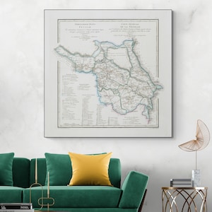 May include: Framed vintage map of Georgia, featuring detailed cartography with text in multiple languages. The map is in a white frame, displayed above a green sofa with a yellow pillow. A gold-colored decorative sculpture is on a side table.
