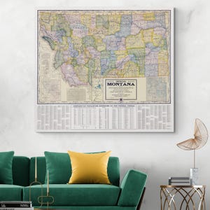 May include: A framed vintage map of Montana, featuring detailed county lines and a color-coded design. The map includes text indicating it is the "Latest Official Survey" and includes a section with population data. The frame is white.