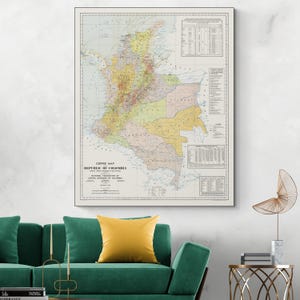 May include: A framed vintage map of Colombia, labeled "Coffee Map Republic of Colombia." The map features a detailed, colorful illustration of the country's regions, with text and charts. The map is displayed above a green sofa with a yellow pillow.
