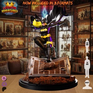 May include: A detailed figurine of a superheroine in a dynamic pose, wearing a black and yellow costume with a flowing cape. The figure stands on a stylized base, with the text "NOW INCLUDED IN 3 FORMATS". The figure is approximately 7.5 cm tall.