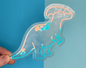 May include: A clear sticker of a light blue and pink dinosaur with a textured pattern. The dinosaur has a large head with a crest and a long tail.