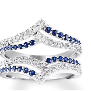 May include: A silver ring with a double-pronged design, featuring a row of small blue sapphires and clear diamonds on each prong.