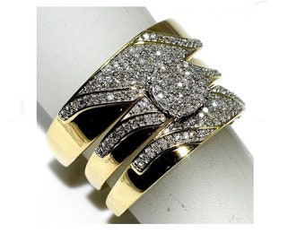 Könnte beinhalten: Drei goldene Eheringe mit einem Diamantenmuster. Der mittlere Ring hat einen größeren Diamantenhaufen.