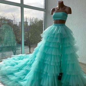 May include: A light blue tulle skirt with multiple layers and a matching strapless top. The skirt has a high waist and a long train.