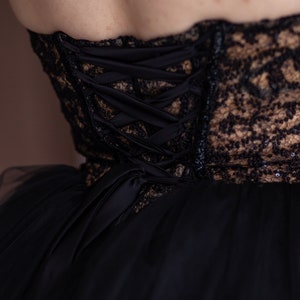 May include: Black lace and tulle dress with a corset back featuring a satin ribbon lacing system.