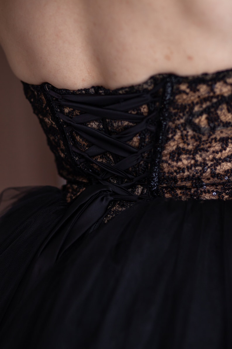 May include: Black lace and tulle dress with a corset back featuring a satin ribbon lacing system.