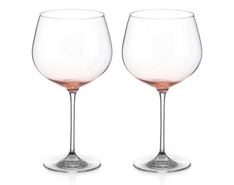 May include: Two clear glass wine glasses with a pink rim. The glasses are empty and have a tall stem.
