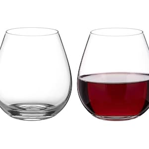 May include: Two clear glass wine glasses, one empty and one filled with red wine.
