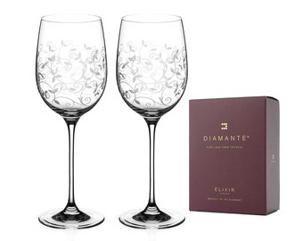 May include: Two clear wine glasses with a decorative floral pattern and long stems. A maroon box with the text "Diamante" and "Elixir Collection" is next to the glasses. The glasses are lead-free crystal.