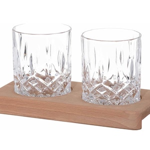 Op de afbeelding: Twee heldere glazen tumblers met een diamantpatroon staan op een houten dienblad. Het dienblad is lichtbruin en heeft een rechthoekige vorm.