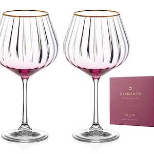 Puede incluir: Juego de dos copas de vino rosa y dorado con diseño acanalado. Las copas forman parte de la colección Diamante Elixir.