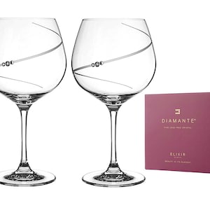 Puede incluir: Dos copas de vino de cristal transparente con un diseño de espiral plateado y un acento de cuentas plateadas. Las copas están sobre un fondo blanco con una caja rosa que dice "Diamante Fine Lead Free Crystal Elixir Beauty in its Element".