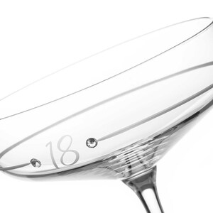 May include: A clear glass champagne flute with a single line etched around the top and the number 18 etched on the side with two small rhinestones.