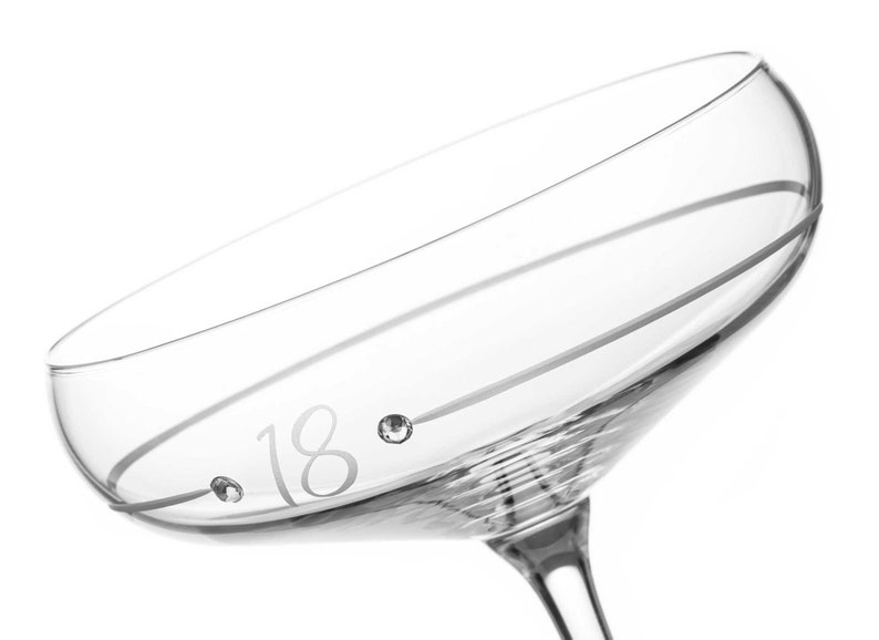 May include: A clear glass champagne flute with a single line etched around the top and the number 18 etched on the side with two small rhinestones.