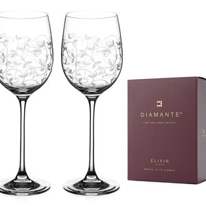 May include: Two clear glass wine glasses with an etched floral design. The glasses are packaged in a burgundy box with the text "Diamante Fine Lead Free Crystal Elixir Collection Beauty in its Element".