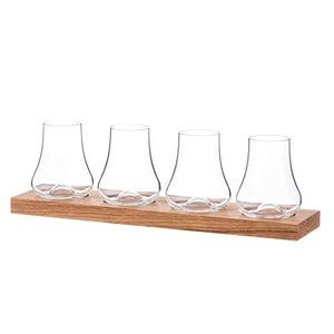 May include: Four clear glass whiskey glasses with rounded bottoms sit on a wooden tray. The glasses are arranged in a row, with the tray extending beyond the edges of the glasses.