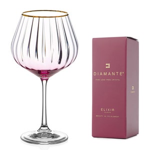 May include: A pink and gold wine glass with a ribbed design. The glass is part of the Diamante Elixir collection, which is made of fine lead-free crystal.
