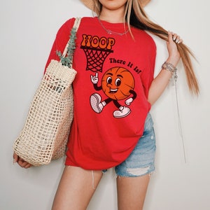May include: Red t-shirt with a cartoon basketball graphic and the text "HOOP There It Is!"