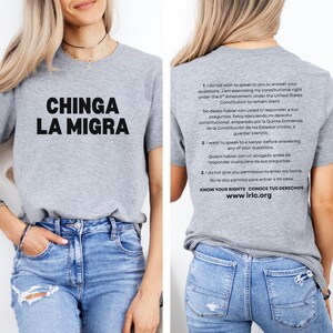 May include: A gray t-shirt with the phrase "CHINGA LA MIGRA" in large black letters. The back of the shirt has text in English and Spanish about constitutional rights, including "KNOW YOUR RIGHTS" and the website www.irlc.org.