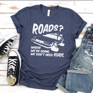 May include: A navy blue t-shirt with a white graphic of a DeLorean time machine and the text "Roads? Where we're going, we don't need roads."