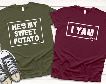 May include: Two t-shirts with a matching couple's design. One shirt is olive green with the text "He's my sweet potato" in a white box. The other shirt is burgundy with the text "I yam" in a white box.