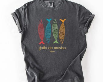 Pode incluir: Uma camiseta cinza escura com um visual vintage que apresenta um gráfico de quatro peixes coloridos e o texto "golfo de mexico 1550".