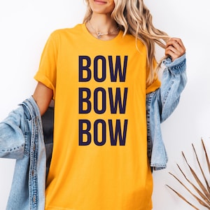 May include: A yellow t-shirt with the text "BOW BOW BOW" printed in dark blue.
