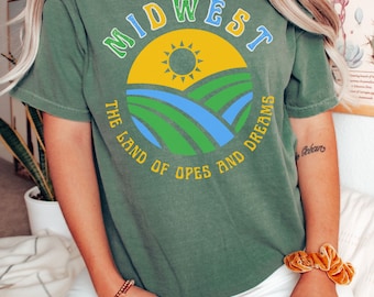 May include: Green t-shirt with a vintage-style graphic of a sun, fields, and the text "MIDWEST THE LAND OF OPES AND DREAMS".
