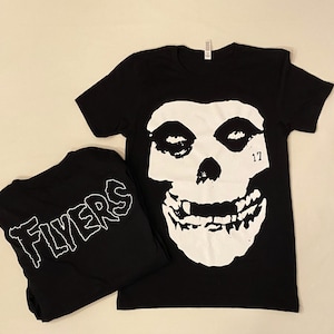 May include: Two black t-shirts, one with a white skull graphic and the text "17" and the other with the text "Flyers" in white.