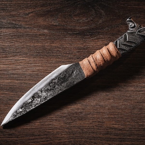 May include: A handcrafted knife with a brown leather wrapped handle and a detailed metal head. The blade is made of metal and has a rustic finish.