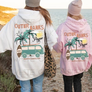 May include: Two people wearing white and pink hoodies with a graphic print of a teal van with palm trees and the text "Outer Banks Pogue Life OBX North Carolina".
