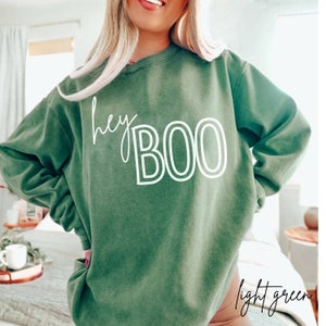 May include: A light green sweatshirt with the text "hey BOO" in white outlined letters.
