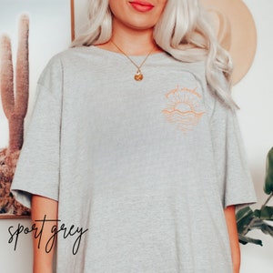 May include: A heather grey t-shirt with a graphic of a sunset over the ocean and the text "sunset somewhere".